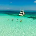 people on body of water across white yacht