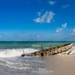 a boat sitting on top of a sandy beach next to the ocean